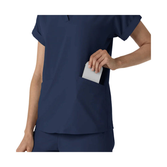 Navy scrub top with short sleeves and chest pocket, shown with a phone tucked into the pocket
