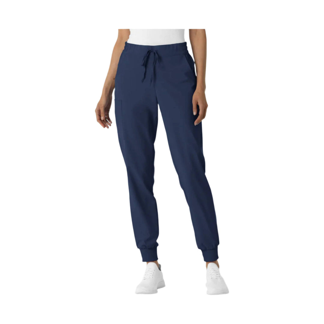 Navy jogger scrub pants with drawstring waist and tapered cuffs, shown on a model with white sneakers.