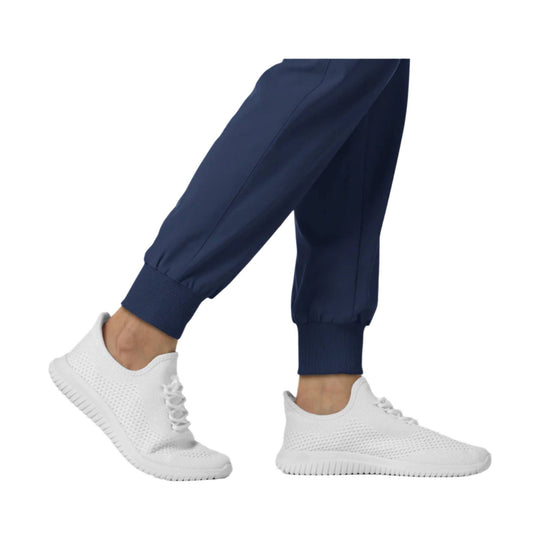 Navy jogger scrub pants with ribbed cuffs, shown on lower legs with white knit sneakers