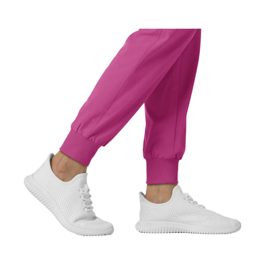 Pink jogger scrub pants with ribbed cuffs, shown on a model with white sneakers