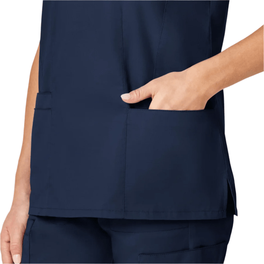 Navy scrub top with a chest pocket and a hand in the side pocket