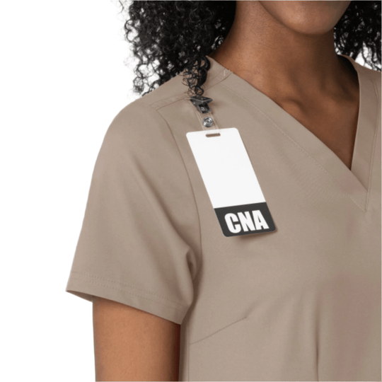 Beige V-neck scrub top with short sleeves and a hanging CNA tag