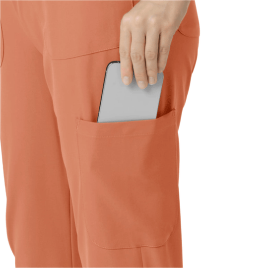 Terra cotta scrub pants with a cargo pocket holding a smartphone