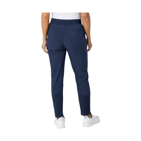 Navy scrub pants with elastic waist, multiple pockets, and tapered legs, shown from the back