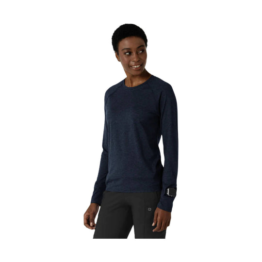 Navy long-sleeve athletic top with crew neck and thumbhole cuffs, shown on a model
