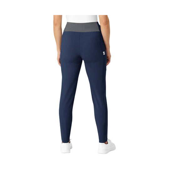 High-waisted navy athletic pants with a gray waistband, back view, worn with white sneakers.