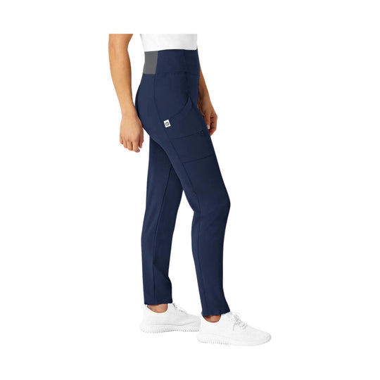 Navy high-waist scrub pants with side pockets and tapered legs, shown on a model with white sneakers