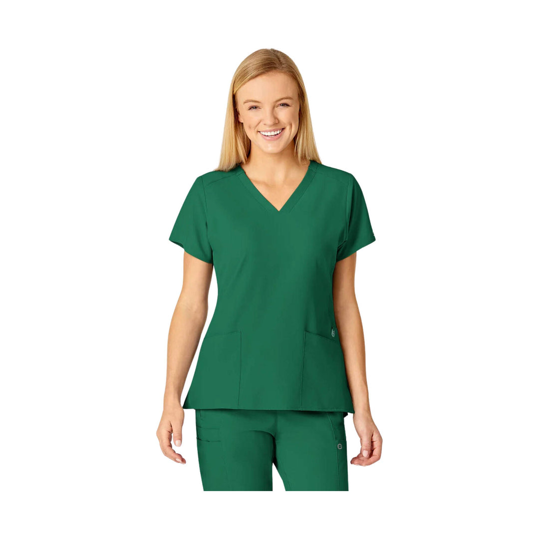 Woman wearing a green V-neck scrub top and matching scrub pants on a white background
