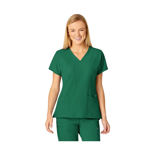 Woman wearing a green V-neck scrub top and matching scrub pants on a white background