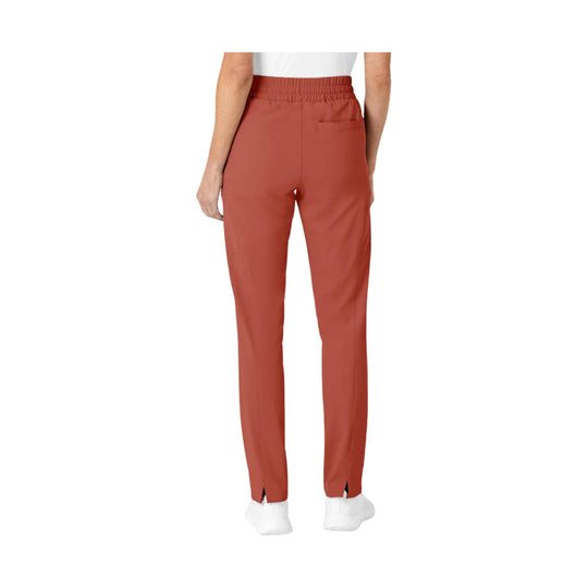 Back view of rust-red slim-leg scrub pants with elastic waistband and slit hems