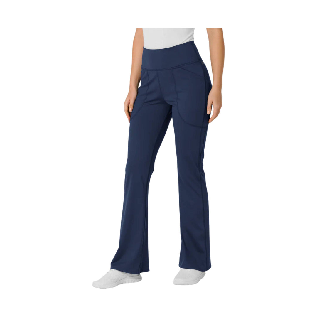 Navy flared yoga scrub pants with a wide waistband and side pockets, shown on a model