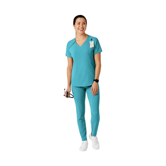 Teal short-sleeve scrub top and matching pants worn with white sneakers