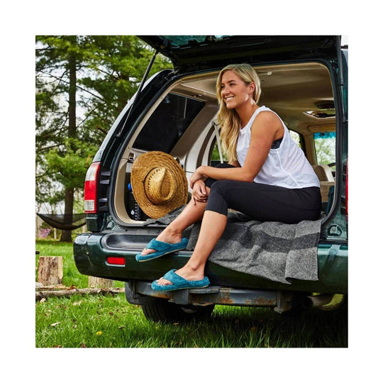 Blue terry thong slippers worn with black leggings, resting on a car tailgate