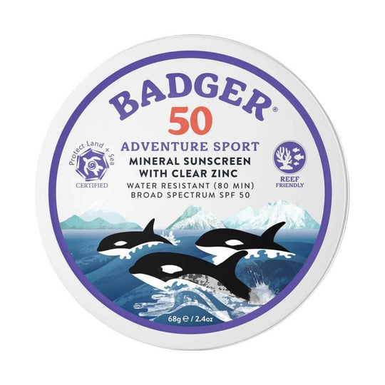 Round white sunscreen tin with purple label, sea-and-orca illustration, and SPF 50 text.