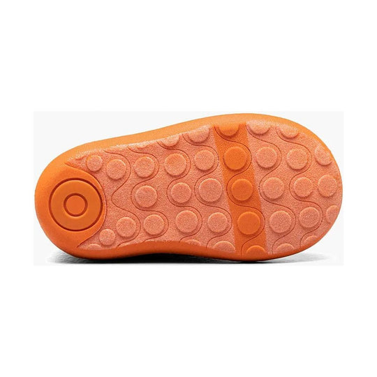 Orange boot sole with circular traction pods and a textured tread pattern