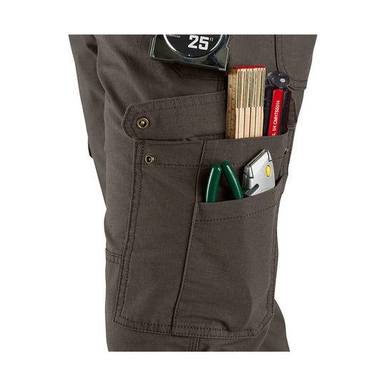 Dark brown cargo work pant leg with multiple tool pockets and a tape measure, ruler, pliers, and utility knife in the pockets