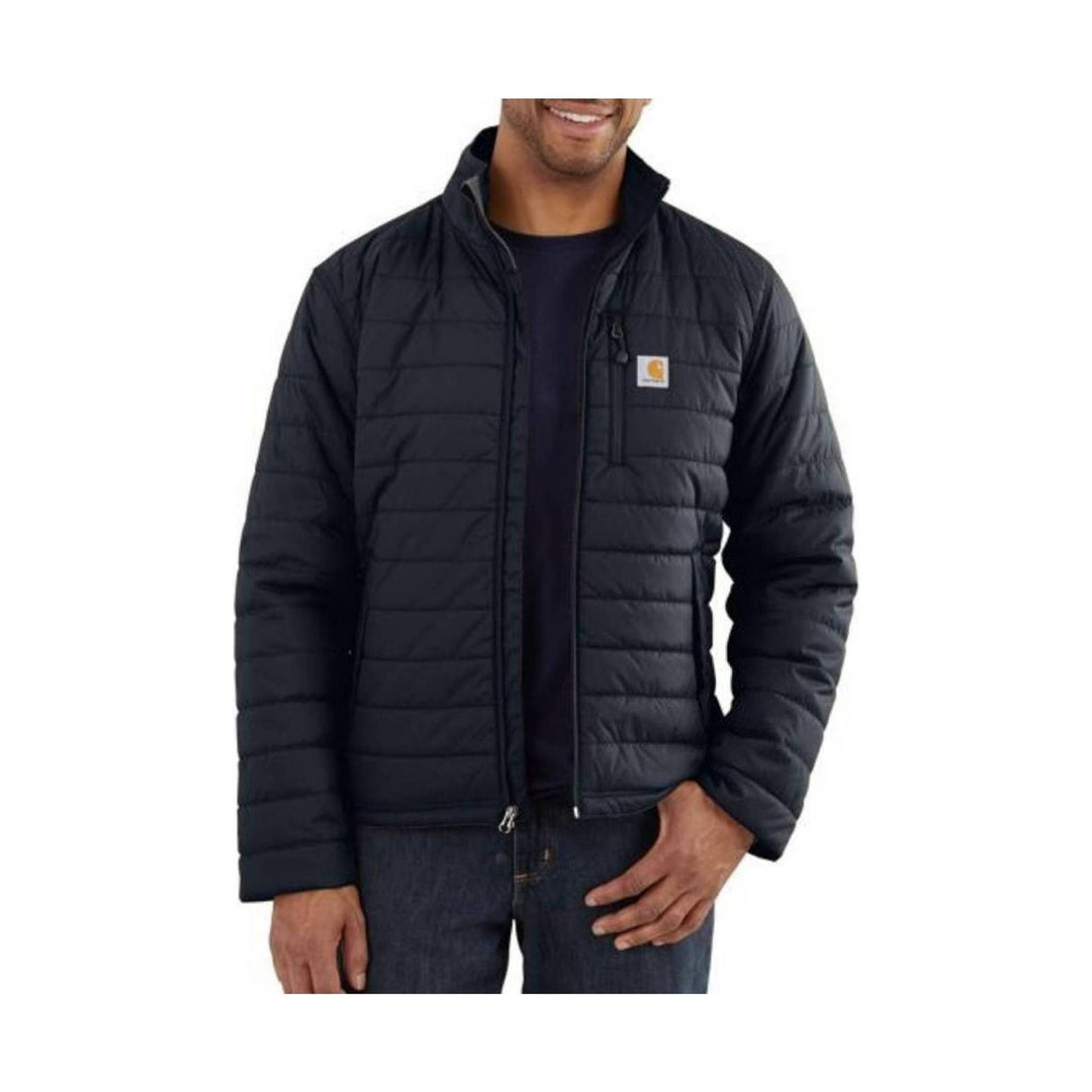 Black quilted insulated jacket worn over a dark shirt, with a stand collar and chest logo patch.