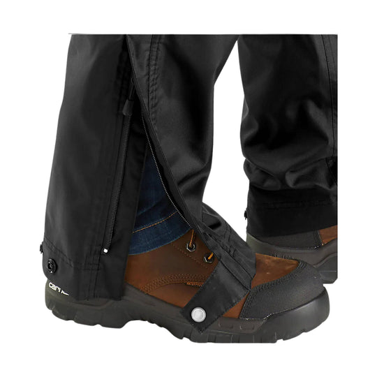 Black rain pants with side zipper gussets over brown hiking boots