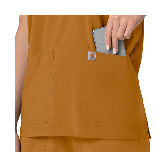 Mustard scrub top with large front pockets and a side pocket holding a phone