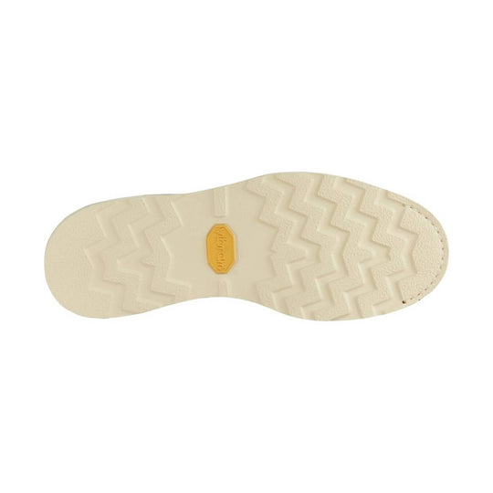 Beige boot outsole with zigzag tread and a yellow Monarch logo insert