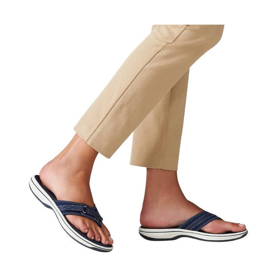 Navy slip-on sandals with white striped soles on a model wearing beige pants