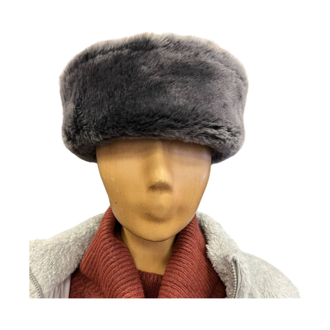 Black faux fur hat on a mannequin wearing a cream sherpa jacket and rust sweater