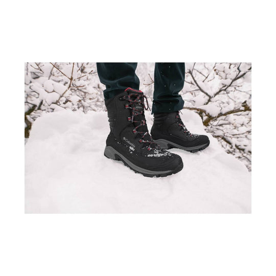 Black winter boots with red laces standing in snow