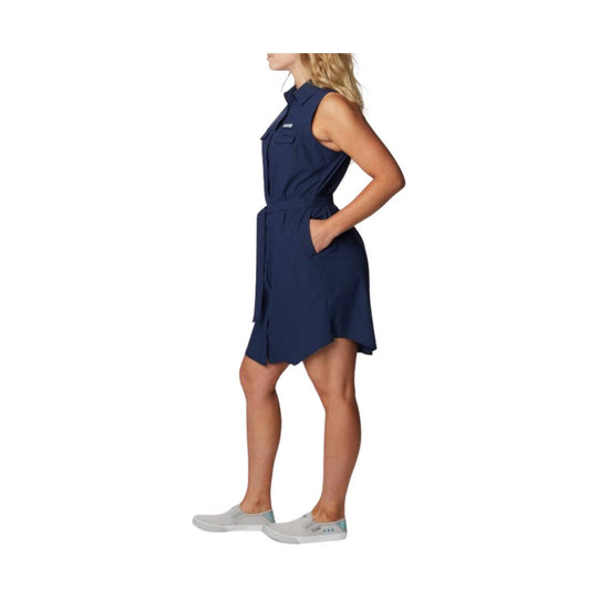 Sleeveless navy belted dress with collar, chest pocket, and hand pockets, shown in side view