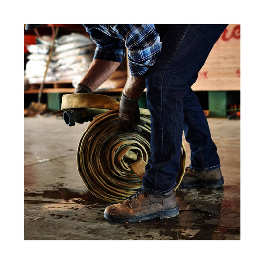 Brown leather lace-up work boot with dark sole, shown on a person rolling a hose in a warehouse