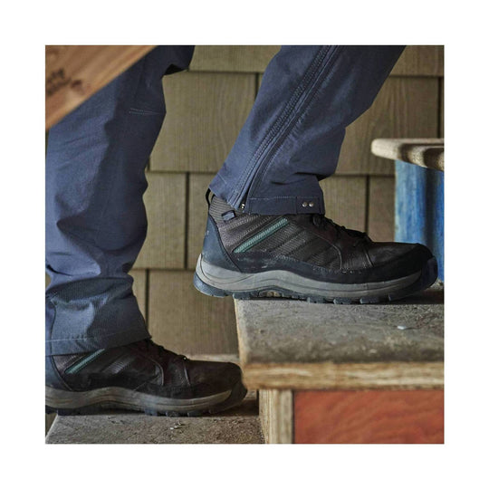 Dark brown and gray high-top work shoe with a side zipper and rugged sole, worn with navy pants