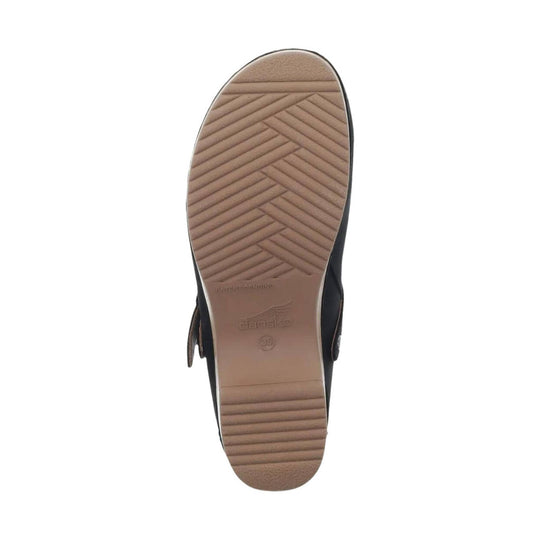Black closed-toe shoe shown from the sole, with a tan treaded outsole and buckle strap visible at the side.