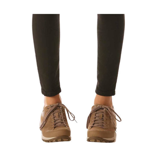 Brown lace-up hiking shoes shown on a model's feet with black pants