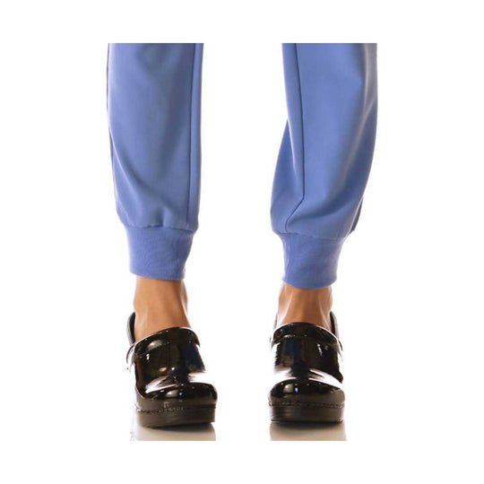 Black patent leather clogs with thick soles, shown from the front on a model's feet