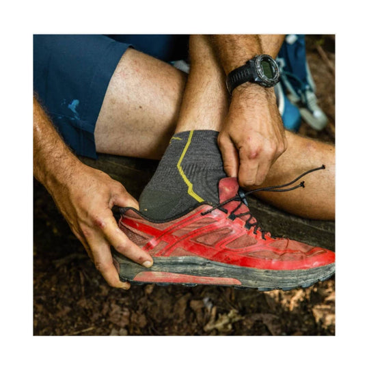 Gray hiking sock with yellow stripe being worn with a red trail shoe