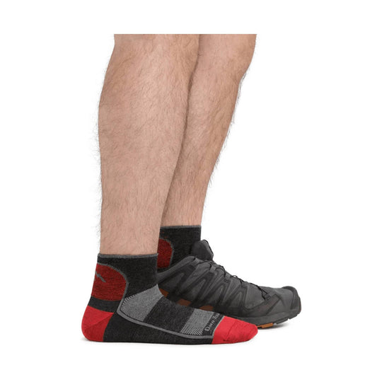 Black, gray, and red quarter athletic sock with reinforced heel and toe, shown worn with a trail shoe