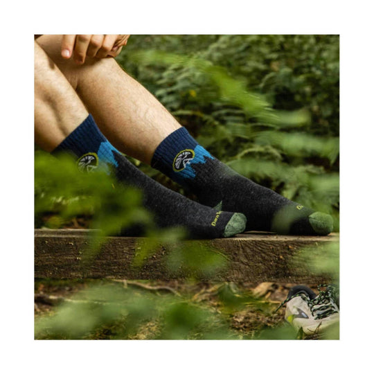 Black hiking socks with blue cuffs and green toe and heel accents worn outdoors.