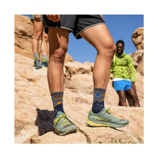 Gray hiking socks with blue mountain graphics and rainbow stripes worn with trail shoes