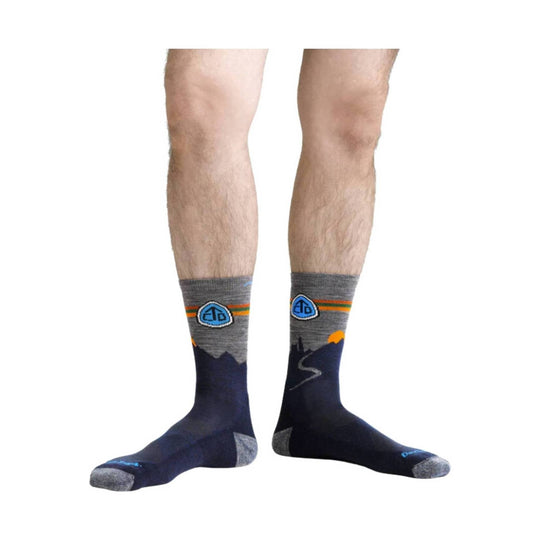 Pair of gray and navy mid-calf hiking socks with mountain and trail graphics shown on legs