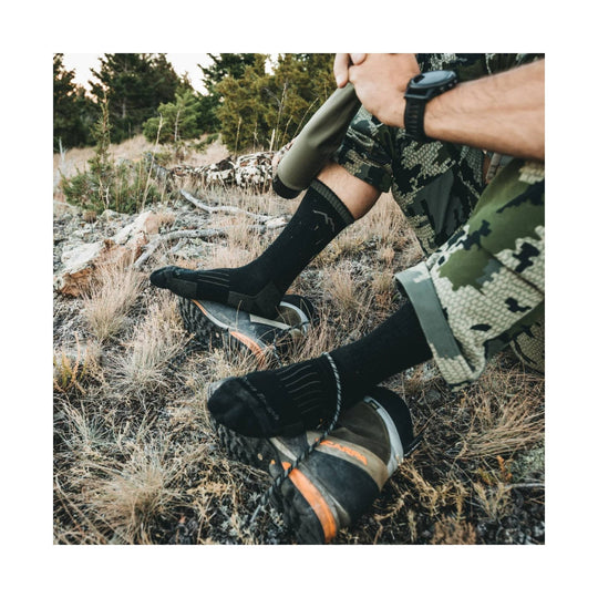 Black midweight hiking socks worn with camo shorts and trail shoes outdoors