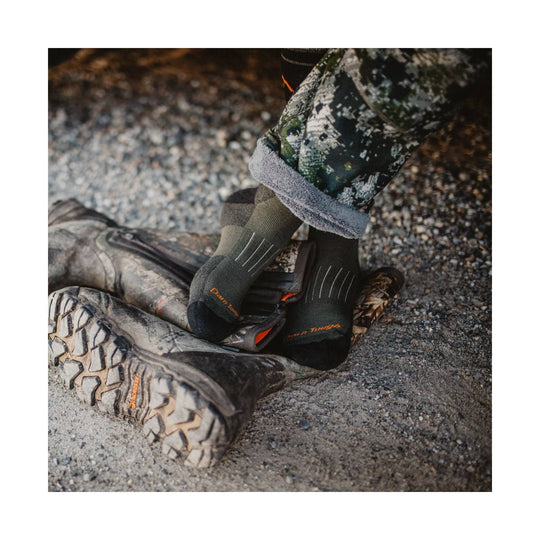 Forest green heavyweight hiking socks worn with camouflage pants and muddy trail boots