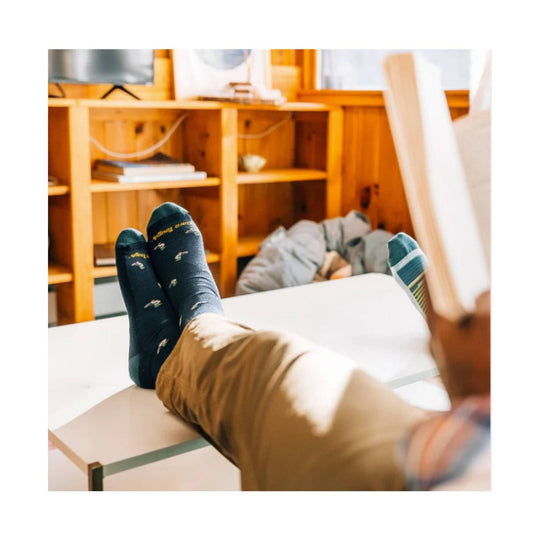 Navy crew socks with small moose pattern on feet resting on a table
