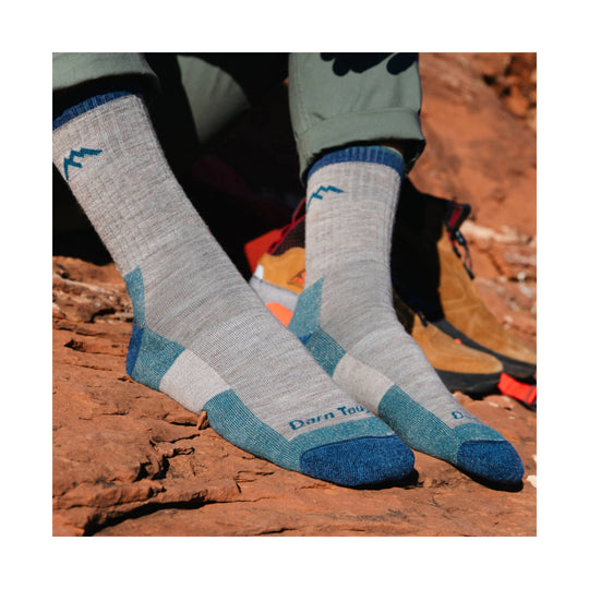 Gray hiking socks with blue toe, heel, and cuff accents, worn with hiking shoes on red rock