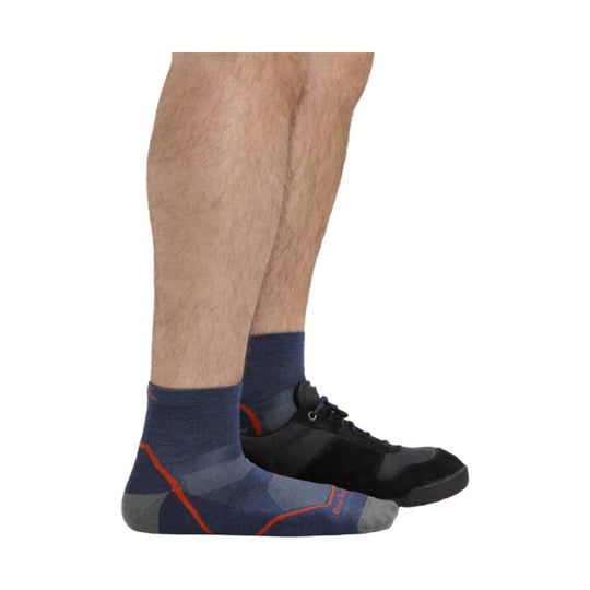 Blue and gray ankle sock with orange accents worn with black athletic shoes