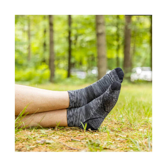Two gray quarter-length hiking socks on crossed legs outdoors on grass