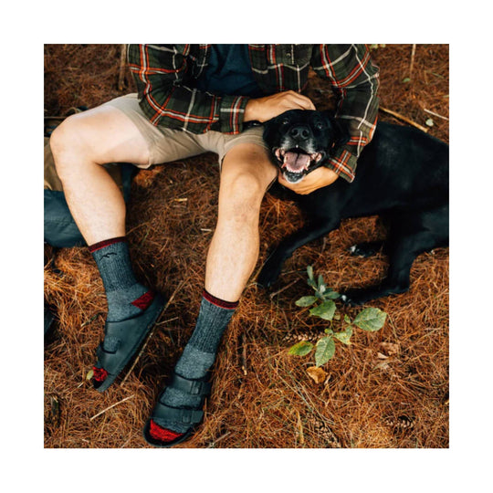 Gray crew socks with red accents worn with black slip-on sandals