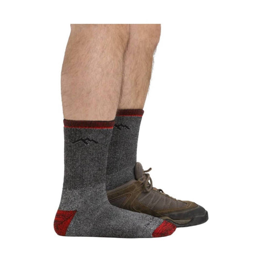 Gray crew socks with red accents and a black mountain logo, worn with brown hiking shoes.