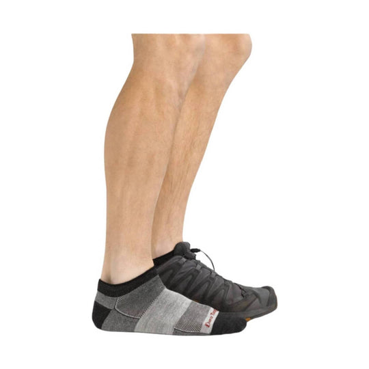 Gray and black low-cut running sock on a model wearing black trail shoes