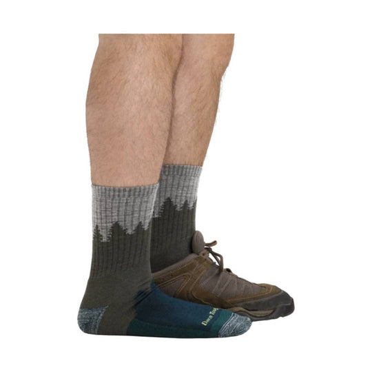 Midweight hiking socks in gray, black, and teal with tree pattern, worn with hiking shoes