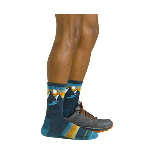 Blue crew socks with mountain and sunset pattern, shown with gray trail shoes