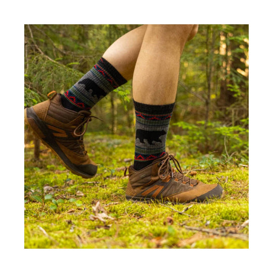 Brown hiking boots with black-and-red patterned crew socks on a forest trail